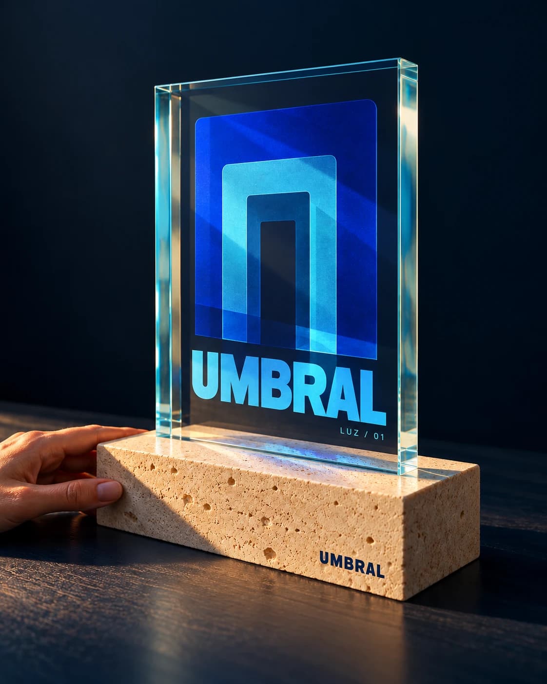 Umbral Luz 01: identidad gráfica cian y cobalto impresa sobre vidrio y base de piedra